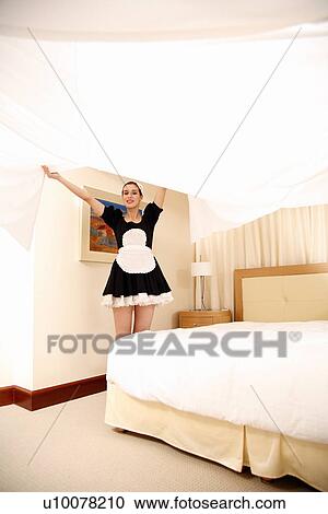 Stock Image - Hotel maid making the bed. Fotosearch