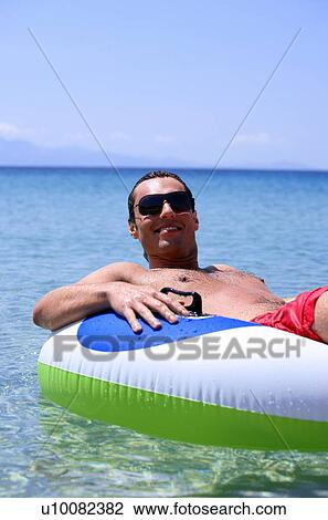 Stock Image - Young man in water on inflatable life ring. Fotosearch