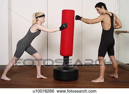 Stock Photograph - Young man and woman practicing with a punching bag. Fotosearch
