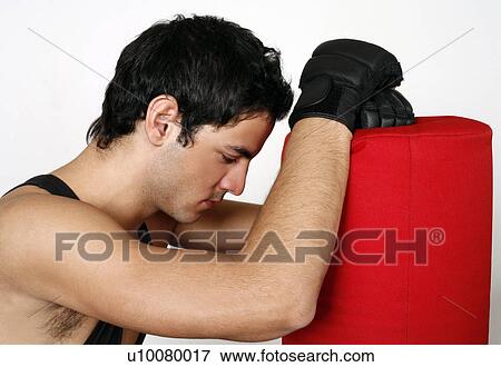 Stock Photo - Young man leaning on punching bag. Fotosearch