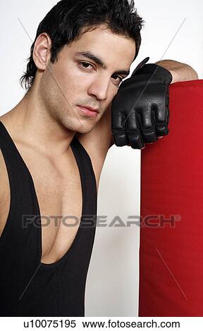 Stock Photography - Young man leaning on punching bag. Fotosearch