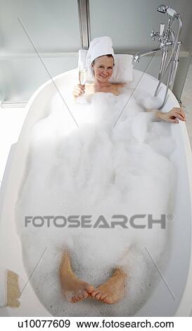 Stock Photo - Mature woman enjoying bubble bath. Fotosearch