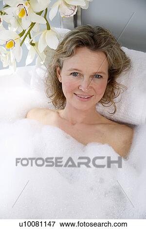 Stock Photo - Mature woman enjoying bubble bath. Fotosearch