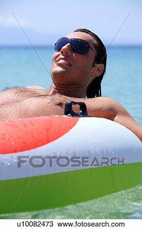 Young man in water on inflatable life ring View Large Photo Image Stock Image - Young man in water on inflatable life ring. Fotosearch