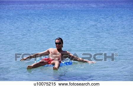 Stock Photography - Young man in water on inflatable life ring. Fotosearch