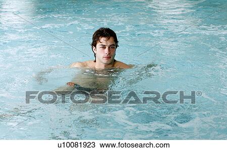 Stock Image - Young man swimming in spa pool. Fotosearch