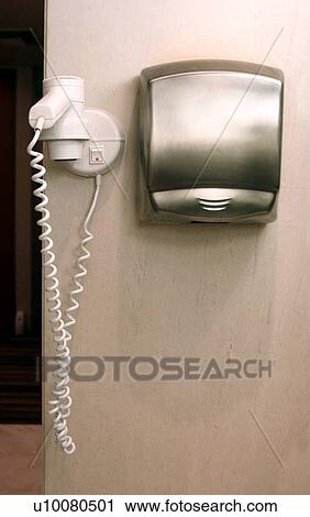 Stock Image - Hair dryer and towel dispenser in bathroom. Fotosearch