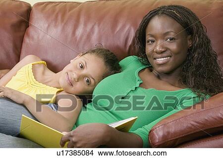 Picture - African American mom and Mulatto girl 6 years. Reading.. Fotosearch