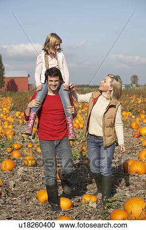 Stock Image - Couple in organic pumpkin patch, Ladner, British Columbia, Canada. Fotosearch