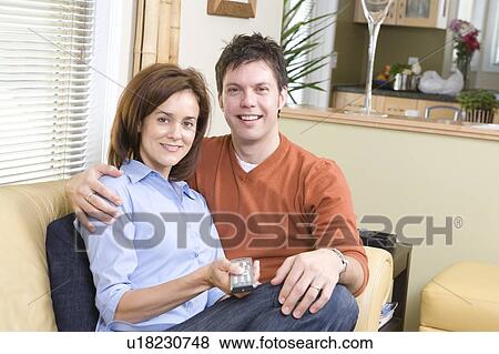 Stock Photo - Couple on sofa with remote contraol, Winnipeg, Canada. Fotosearch