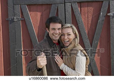 Stock Photograph - Couple stand beside barn, at organic farm, Ladner, British Columbia, Canada. Fotosearch