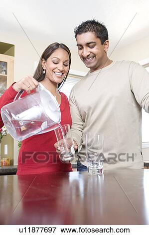 Stock Photo - Woman pouring water from filtre jug, avoiding use of bottled water, Winnipeg, Canada, avoiding use of bottled water. Fotosearch