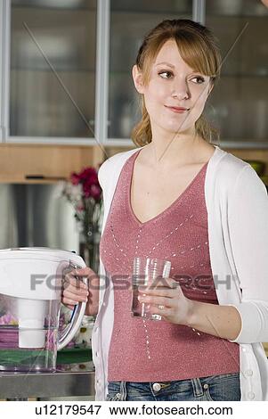 Stock Photo - Woman with glass of water from filtred jug. Fotosearch