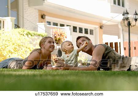 Stock Photo - Young man & woman playing with baby in grass, Regina, Saskatchewan. Fotosearch