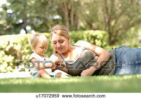 Young woman w/baby in grass, Regina, Saskatchewan View Large Photo Image Stock Photo - Young woman w/baby in grass, Regina, Saskatchewan. Fotosearch