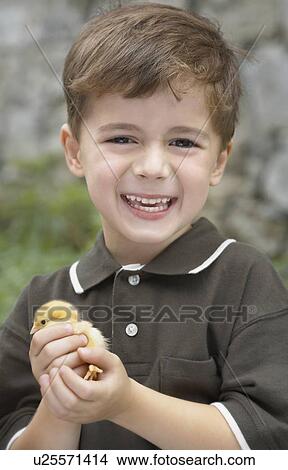 Picture - Little boy holding a baby chick on a farm, Waterford, Ontario. Fotosearch