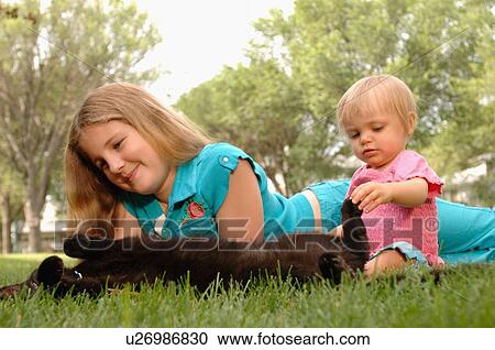 Stock Image - Young girl, baby & cat on grass, Regina, Saskatchewan. Fotosearch