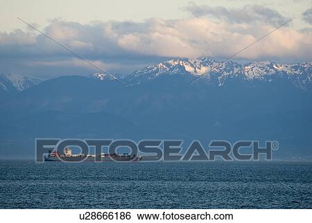 Stock Photograph - Large container ship in front of snow-capped mountains, Victoria, BC, Canada. Fotosearch