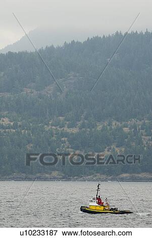 Stock Photo - Tug Boat in the ocean with mountains in the background, Howe Sound, BC. Fotosearch