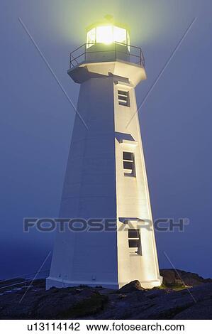 Stock Image - View of Cape Spear Lighthouse in fog at twilight, Cape Spear National Historic Site, Avalon Peninsula, Newfoundland, Canada. Fotosearch