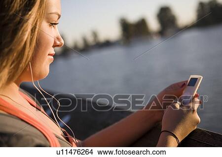 Picture - Female, 17, listening to ipod while on dock, Fraser River, Vancouver, BC. Fotosearch