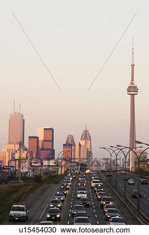 Stock Image - View of Toronto skyline from above Queen Elizabeth Way highway during start of rush hour traffic, Toronto, Ontario, Canada.. Fotosearch