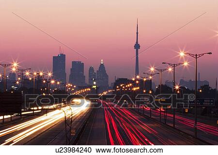 Stock Image - View of Toronto skyline from above Queen Elizabeth Way highway during start of rush hour traffic, Toronto, Ontario, Canada.. Fotosearch