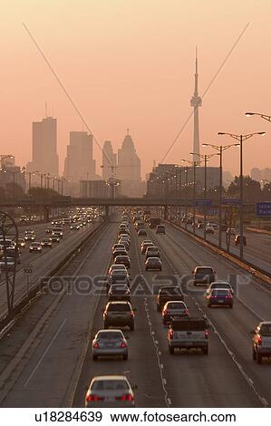 Stock Photo - View of Toronto skyline from above Queen Elizabeth Way highway during start of rush hour traffic, Toronto, Ontario, Canada.. Fotosearch