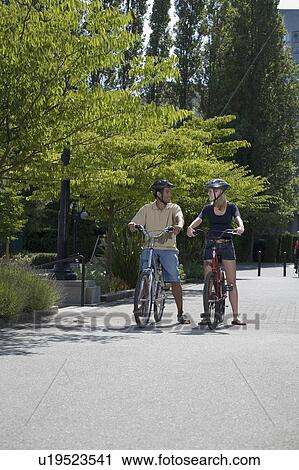 Stock Image - Young Couple Posed on Bicycles on city bike path, Vancouver, British Columbia. Fotosearch