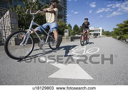 Stock Image - Young Couple Ride Bicycles on city bike path, Vancouver, British Columbia. Fotosearch