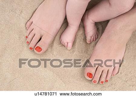 Stock Image - Baby feet and a Woman's feet at the Beach. Fotosearch
