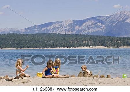 Stock Photo - Children playing on beach on Lake Koocanusa in the East Kootenays near Fernie, British Columbia, Canada. Fotosearch