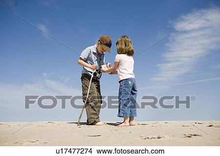 Picture - Four year old girl and seven year old boy look at shell, Grand Beach Provincial Park, Manitoba, Canada. Fotosearch