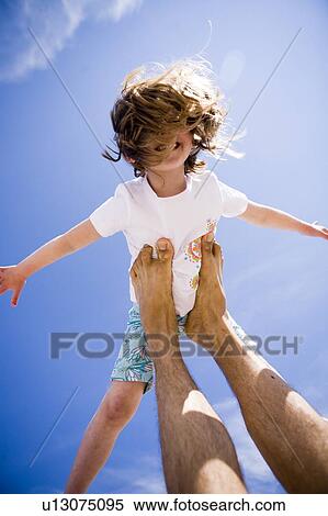 Stock Photography - Girl (4) does "airplane" balancing on adult's feet, Grand Beach, Manitoba, Canada. Fotosearch