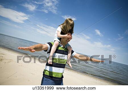 Stock Photo - Girl (4) rides on man's shoulders, Grand Beach Provincial Park, Manitoba, Canada. Fotosearch