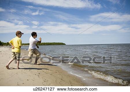 Stock Photo - Man and boy (7) skipping stones, Grand Beach Provincial Park, Manitoba, Canada. Fotosearch