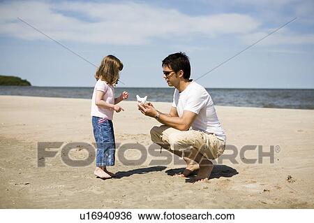 Man and girl (4) look at shell at beach, Grand Beach Provincial Park, Manitoba, Canada View Large Photo Image Stock Photograph - Man and girl (4) look at shell at beach, Grand Beach Provincial Park, Manitoba, Canada. Fotosearch