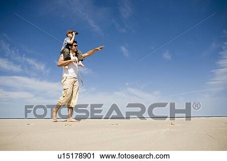 Stock Image - Man carries boy (7) on his shoulders, Grand Beach Provincial Park, Manitoba, Canada. Fotosearch