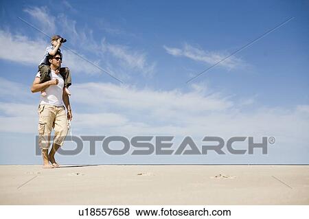 Stock Photo - Man carries boy (7) on his shoulders, Grand Beach Provincial Park, Manitoba, Canada. Fotosearch