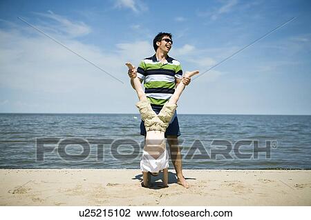 Stock Image - Man holds boy upside down, Grand Beach Provincial Park, Manitoba, Canada. Fotosearch