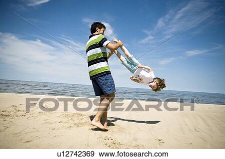 Stock Photo - Man swings girl (4) around by her feet, Grand Beach Provincial Park, Manitoba, Canada. Fotosearch
