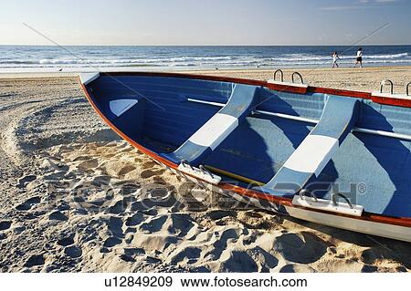 Stock Photo - Women walking on beach and small boat, New Jersy, USA.. Fotosearch