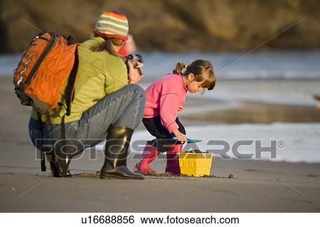 Young mother videos daughter play on beach in Harris Beach State Park, Oregon, USA View Large Photo Image Stock Photograph - Young mother videos daughter play on beach in Harris Beach State Park, Oregon, USA. Fotosearch