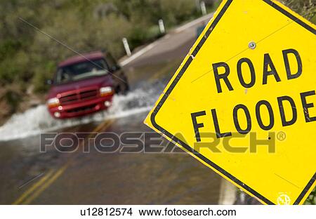 Picture - Vehicle driving on flooded road. Fotosearch