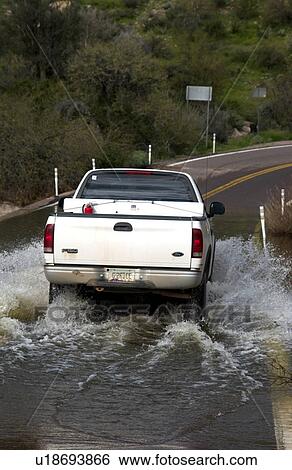 Stock Photograph - Vehicle driving on flooded road. Fotosearch