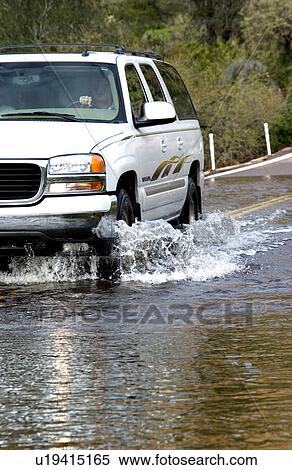 Stock Photography - Vehicle driving on flooded road. Fotosearch