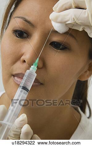Stock Image - Asian woman receiving botox injection. Fotosearch