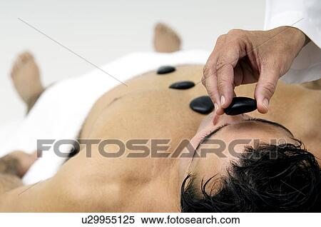 Stock Photography - Man receiving stone therapy. Fotosearch