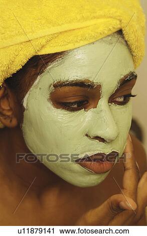 Stock Image - Woman putting on a facial mask. Fotosearch