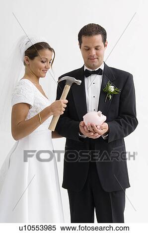 Stock Photography - Bride and groom breaking piggy bank. Fotosearch